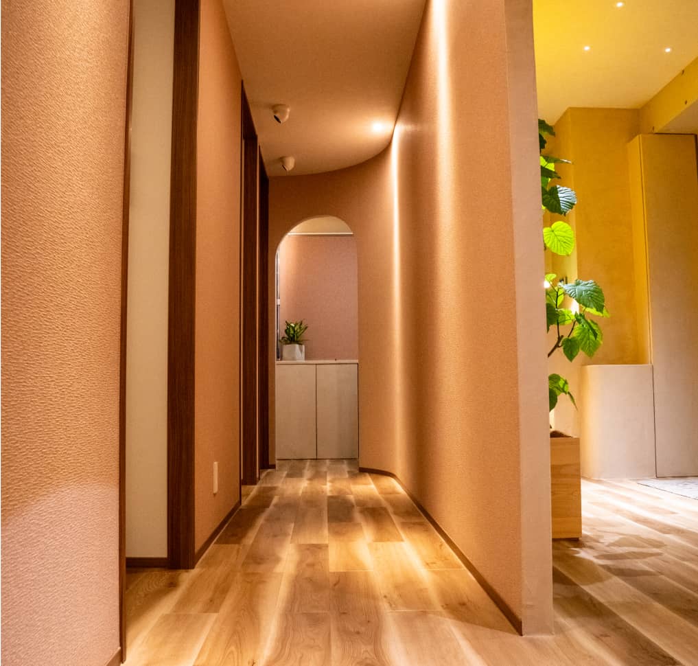 木目調の床と暖かい照明が特徴的な、アーチ状のデザインがあるサロンの廊下