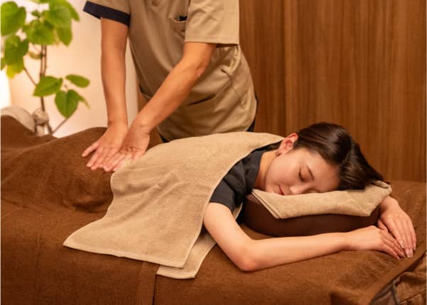 茶色のタオルをかけてリラクゼーションマッサージを受けている女性